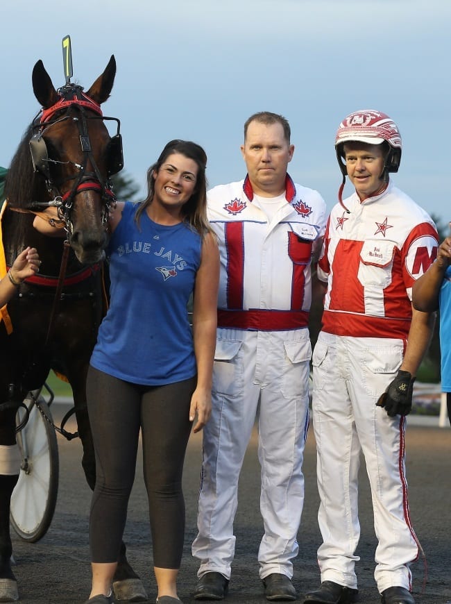 New Image Media | 
Trainer Scott McEneny (center) — with driver Paul MacDonell after a win with trotter Stuck In My Spanks — is having a terrific year with young horses.
