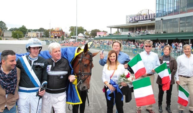 Winning driver Christoffer Eriksson (helmet), trainer Jerry Riordan and Italian owners Pasquale Ciccarelli and his girlfriend, Elena Villani were among an excited group in the winner's circle after Twister Bi dominated the $1 million Yonkers International Trot Saturday afternoon at Yonkers | Mike Lizzi